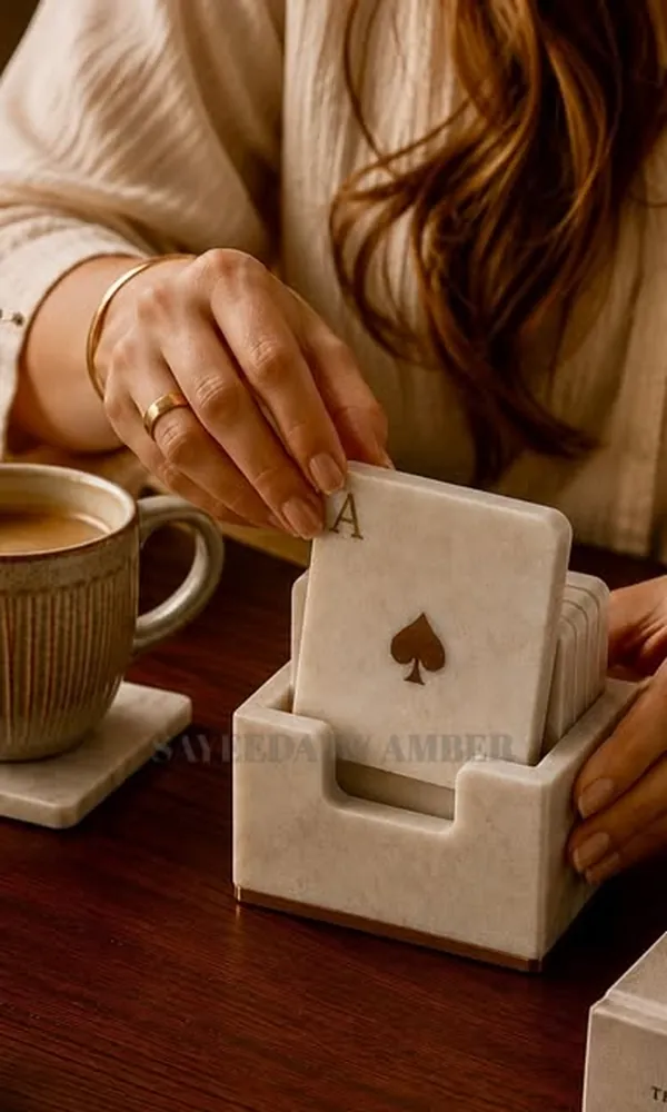 Marble playing-card coasters beside a candle and a cup of tea